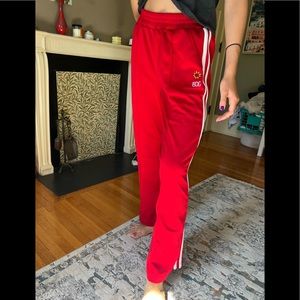 Urban Outfitters BDG Red track pants with three white stripes on the side.